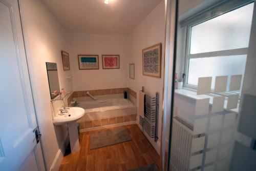 y baño con bañera, lavamanos y bañera. en Warriston Apartment at Holm Park en Moffat