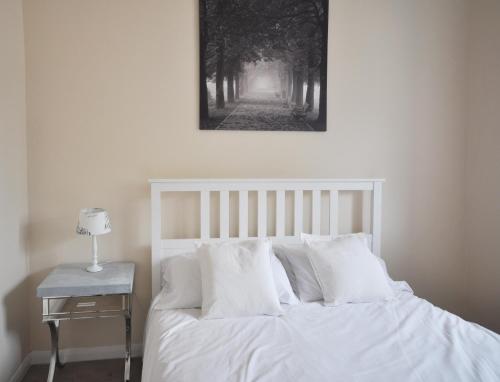 Un dormitorio con una cama blanca con una foto en la pared en Stable Cottage, Whitebridge Farm en Shaftesbury