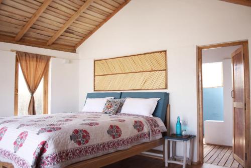 1 dormitorio con 1 cama con techo de madera en The Indus River Camp, en Leh