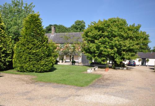 ein Haus mit Bäumen und Bänken davor in der Unterkunft Stable Cottage, Whitebridge Farm in Shaftesbury