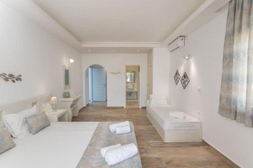 a white bedroom with a large bed and a couch at Keti Kapri in Plaka