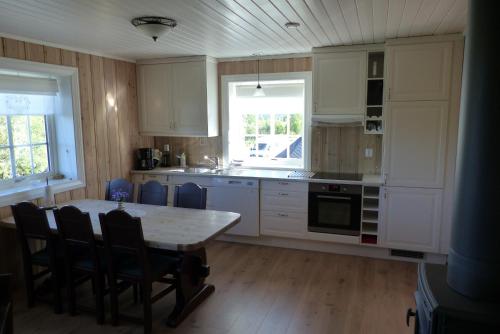 una cocina con armarios blancos y una mesa con sillas. en Skåbu Hytter og Camping, en Skåbu