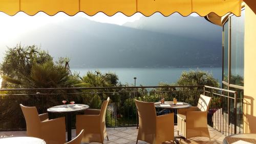 a patio area with chairs, tables and umbrellas at Hotel Mercedes in Limone sul Garda