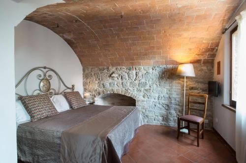 a bedroom with a bed and a brick wall at Leon Bianco in San Gimignano