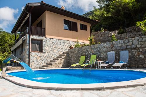 a swimming pool with chairs and a house at Sunset Holiday Home in Tivat