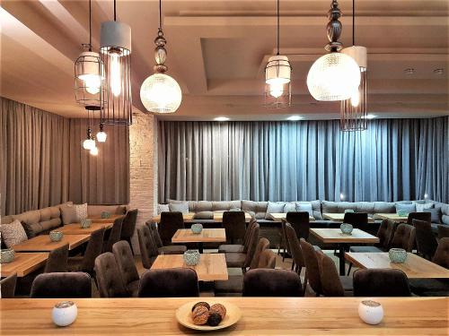 a restaurant with tables and chairs and chandeliers at Chryssi Akti, Sure Hotel Collection in Batsi