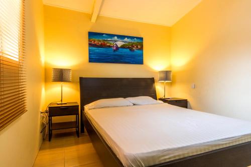a bedroom with a bed with two night stands and two lamps at Advantage Apartments Curacao in Willemstad