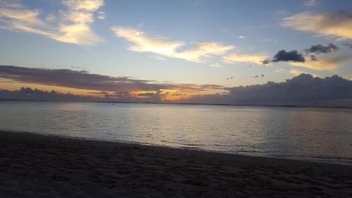 a sunset on the beach with the ocean at Mahina Luxury 2 Bedroom Apartment with Pool in Flic-en-Flac