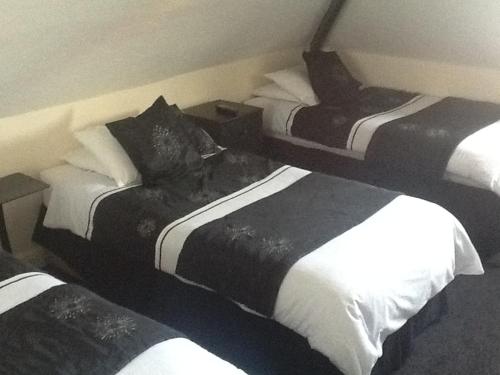 a hotel room with three beds with black and white sheets at George & Dragon in Coleshill