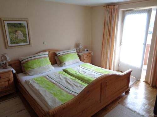 シェーナウ・アム・ケーニッヒスゼーにあるHaus Walchのベッドルーム1室(大型木製ベッド1台、緑のシーツ付)