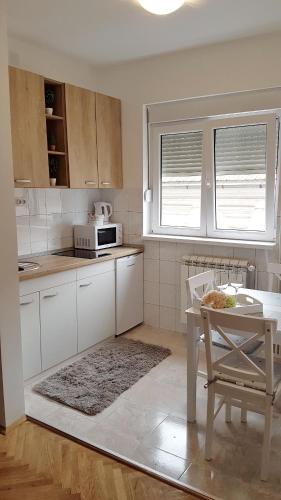 a white kitchen with a table and a microwave at Apartments Spring in Čačak