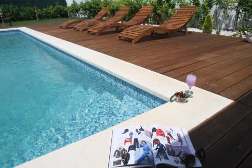 a pool with chairs and a table with a glass of wine at Villa Perlla in Split