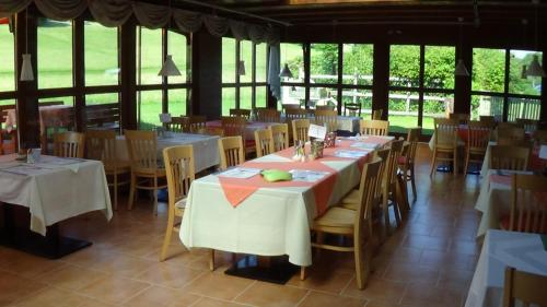 una sala da pranzo con tavoli, sedie e finestre di Familienparadies Reichenhauser a Keutschach am See