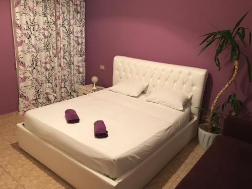 Una cama blanca con dos zapatillas en un dormitorio en Fantasy Beach Apartment, en Golem