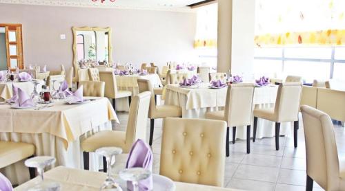 a dining room with tables and chairs with purple napkins at Aurelis Hotel in Bërxull