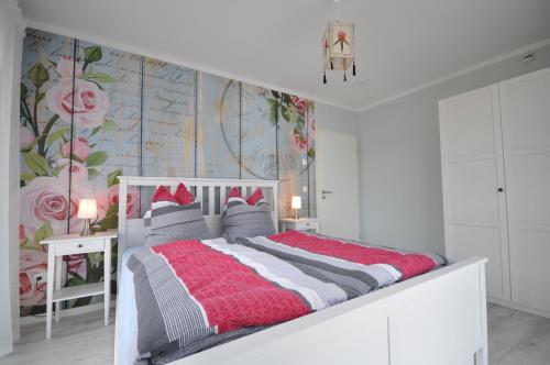 a white bedroom with a bed with a floral wallpaper at Ferienhaus Seerose in Hohenfelden