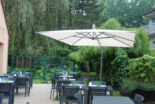 a group of tables and chairs with an umbrella at Campanile Creil - Villers-Saint-Paul in Villers-Saint-Paul