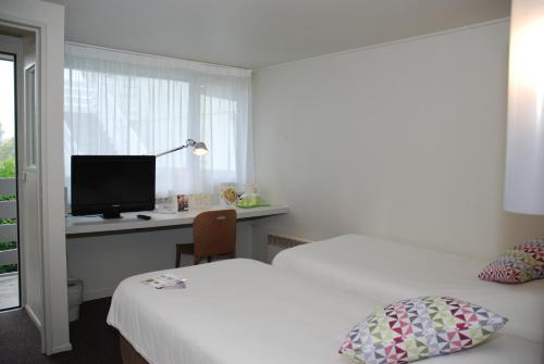 a bedroom with two beds and a desk with a television at Campanile Creil - Villers-Saint-Paul in Villers-Saint-Paul