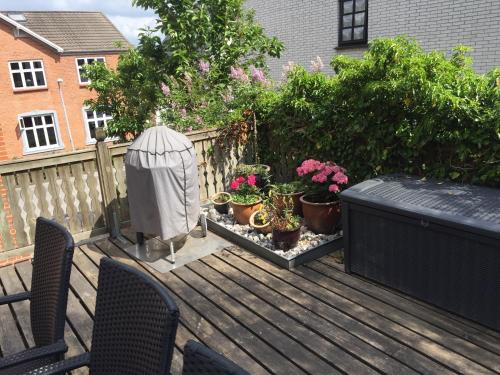 a deck with potted plants and a bird house at Siesta Vejle in Vejle