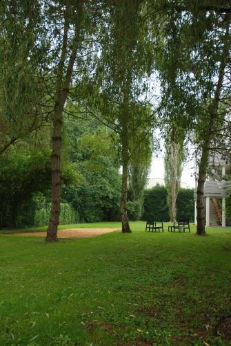 a park with two benches and trees in the grass at Campanile Creil - Villers-Saint-Paul in Villers-Saint-Paul