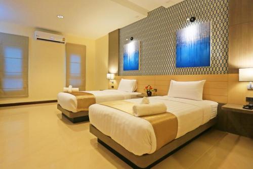 dwa łóżka w pokoju hotelowym z niebieskimi obrazami na ścianie w obiekcie iBiz Boutique Hotel w mieście Nakhon Si Thammarat