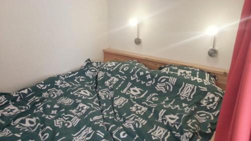 uma cama com um edredão verde e branco e almofadas em studio-appartement in paardenstal em Colijnsplaat