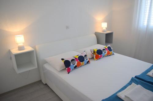 a white bed with two pillows and two lamps at Apartments Milas in Trogir