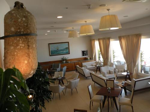 un restaurant avec des tables et des chaises blanches et une salle d'attente dans l'établissement Hotel Parrini, à Follonica