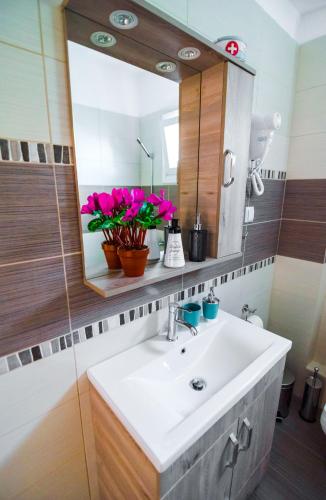a bathroom with a sink and a mirror and flowers at Sea Breeze Flat in Kavála