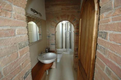 a bathroom with a sink and a toilet and two mirrors at La Fornace di San Galgano in Frosini