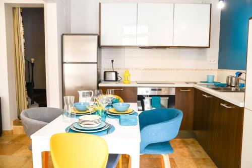 a kitchen with a table with blue chairs and a kitchen with a counter at Le Sureau in Avignon