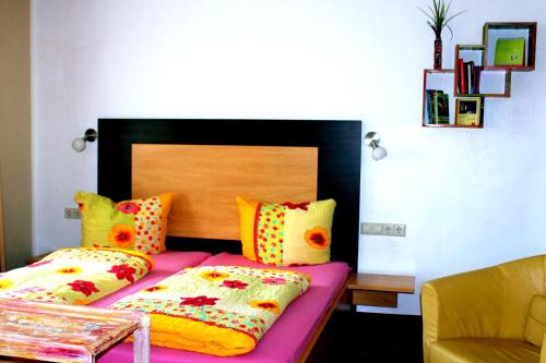 a bedroom with a bed with colorful pillows at Donau Pension in Tuttlingen