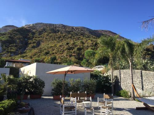 a patio with an umbrella and chairs and a mountain at Casa Arcada in Vulcano