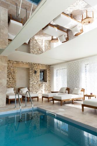 a room with a swimming pool with tables and chairs at Mas des Herbes Blanches Hôtel & Spa – Relais & Châteaux in Joucas
