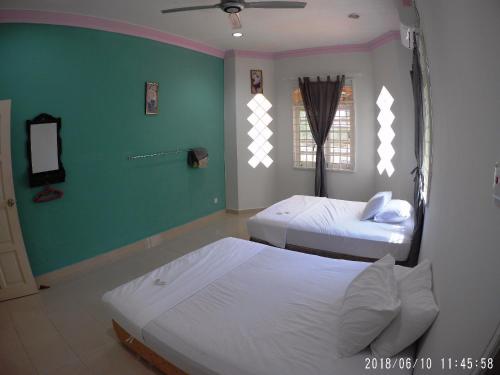a bedroom with two beds and a green wall at FBS Guesthouse Dungun in Dungun