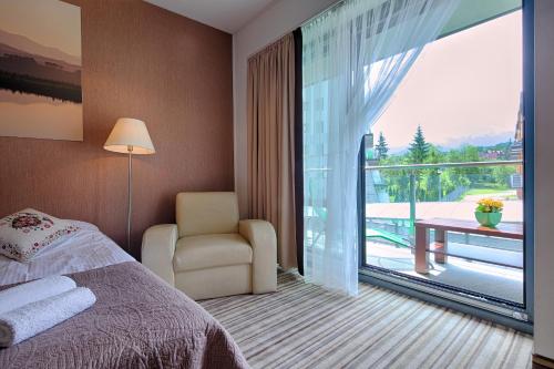 a bedroom with a bed and a balcony with a view at Apartament Szklane Domy in Zakopane