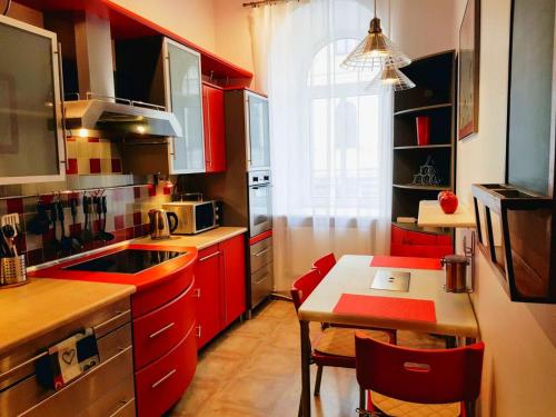eine Küche mit roten Schränken, einem kleinen Tisch und einem Tisch in der Unterkunft Gustav House in Daugavpils