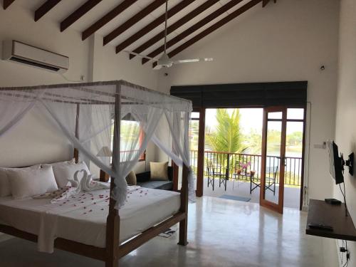 a bedroom with a canopy bed and a balcony at Malu Banna in Aluthgama