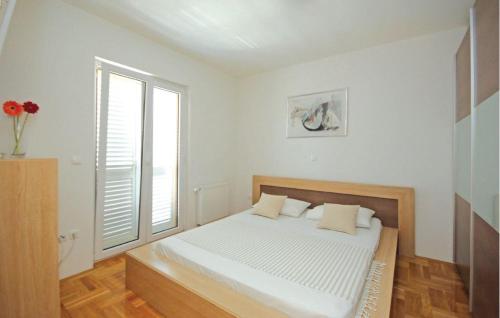a white bedroom with a bed and a window at Apartment SeaSun in Makarska