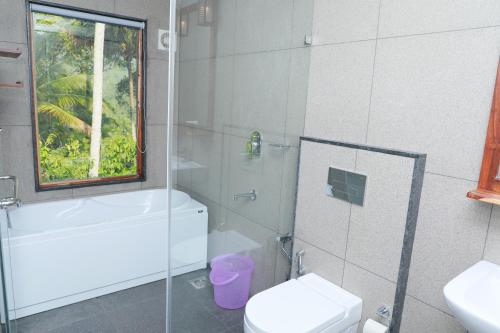 a bathroom with a toilet and a glass shower at Coffee and Pepper Plantation Homestay in Thekkady