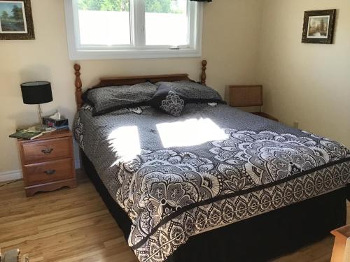 1 dormitorio con 1 cama con edredón blanco y negro en Gîte Au Bord de la Baie, en Bouctouche