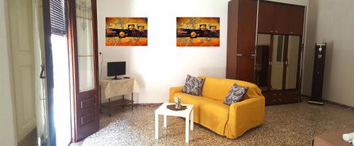 a living room with a yellow chair and a table at Dai nonni in Niscemi