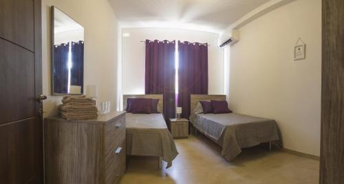 um quarto com 2 camas e uma cómoda com um espelho em Pierre & Liana's place em Msida