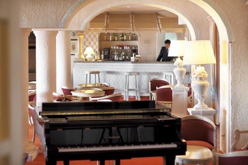 a piano sitting in a room with a bar at Grand Hotel Smeraldo Beach in Baja Sardinia