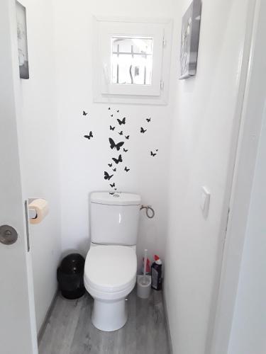 une salle de bain avec des toilettes avec des papillons sur le mur dans l'établissement La Rivière, à Pujols Gironde