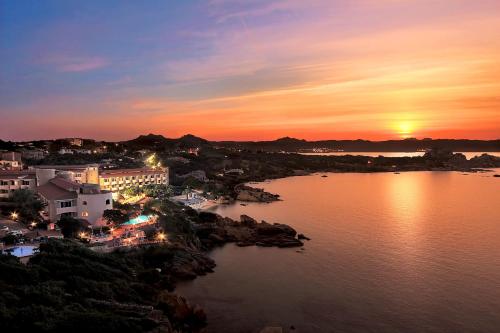 a sunset over a body of water with a city at Grand Hotel Smeraldo Beach in Baja Sardinia