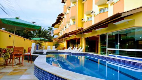 uma piscina ao lado de um edifício com um hotel em Hotel Canto da Riviera em Riviera de São Lourenço