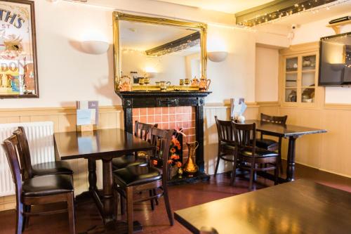 a dining room with tables and a fireplace at The Swan in Thornbury