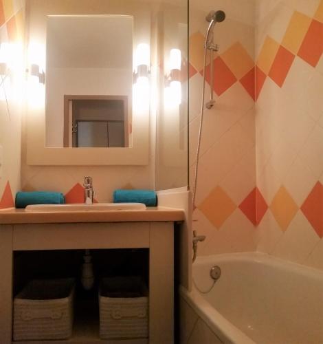 une salle de bain avec un lavabo, un miroir et une baignoire dans l'établissement Sea view La Palme d'Azur apartment steps away from the beach and perfect for holidays & business trips, à Cannes