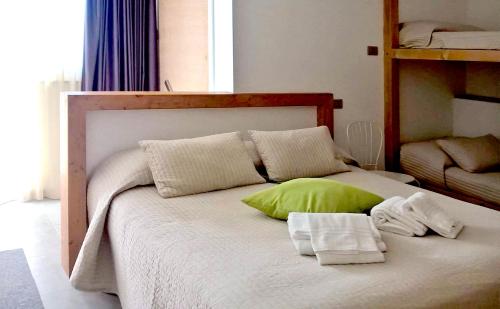 a bed with a green pillow and towels on it at Alfieri Cottage in Ruvo di Puglia